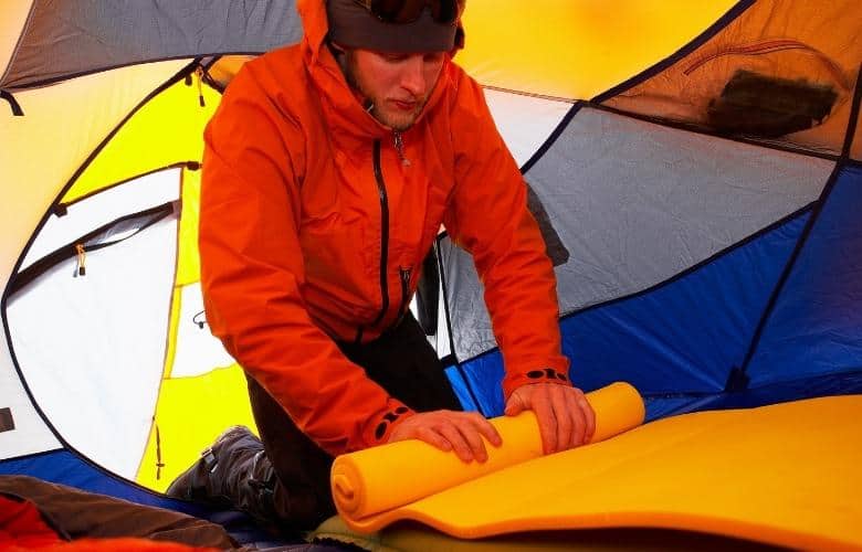 A man preparing the sleeping pad inside a tent