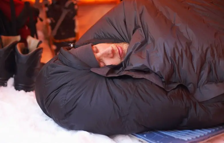 A man sleeping inside a tent while wearing a four-season sleeping bag.