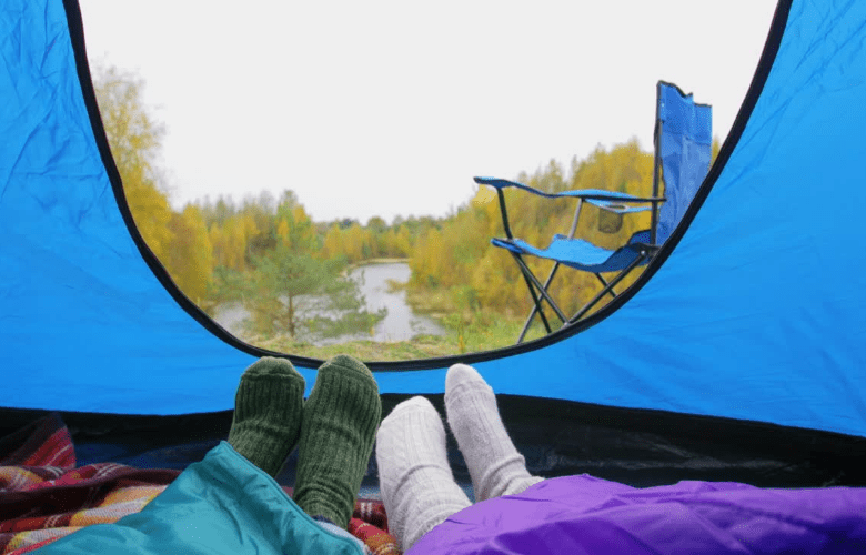 View from a camping tent, with feet in socks and tucked under a sleeping bag